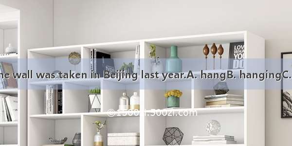 The photo on the wall was taken in Beijing last year.A. hangB. hangingC. hungD. hanged